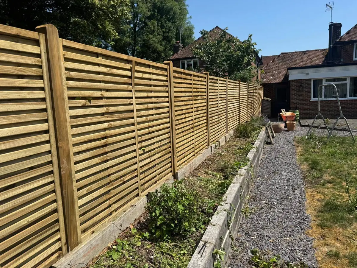 Slatted timber panel fence along a raised garden border, fitted by Tyrrells